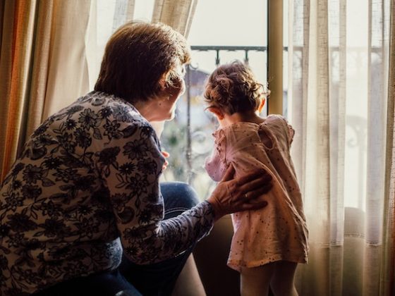 grandma with child looking outside of a window