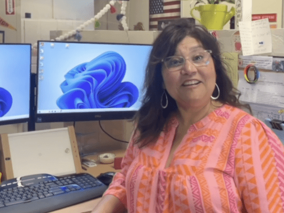 A woman using EVY LIGHT under her screen at the office smiling