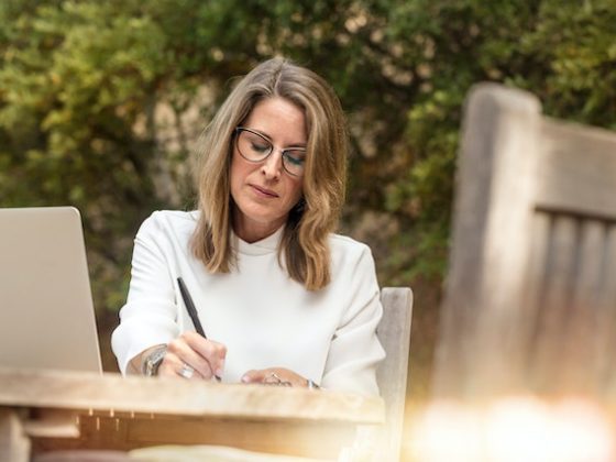 woman sitting outside at a table and writing