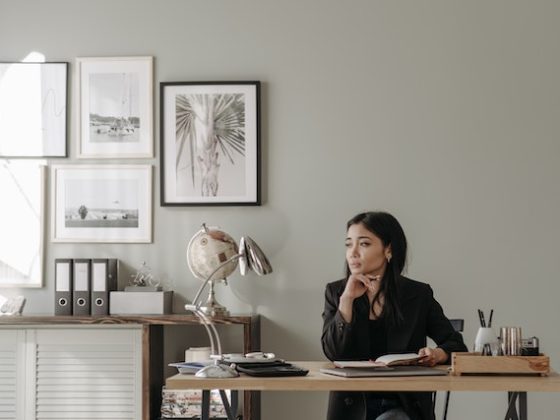 Woman sitting by her desk and thinking while making notes